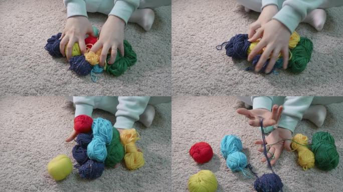 女人的手碰到地板上的几个五颜六色的球和绞线。我的宝贝。
