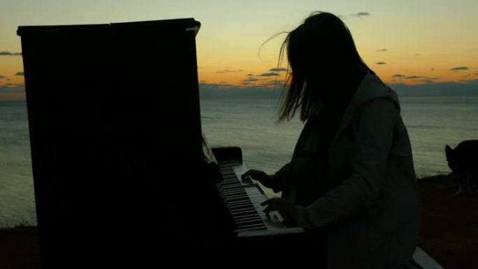 一个女孩在海滩上弹钢琴的日落剪影