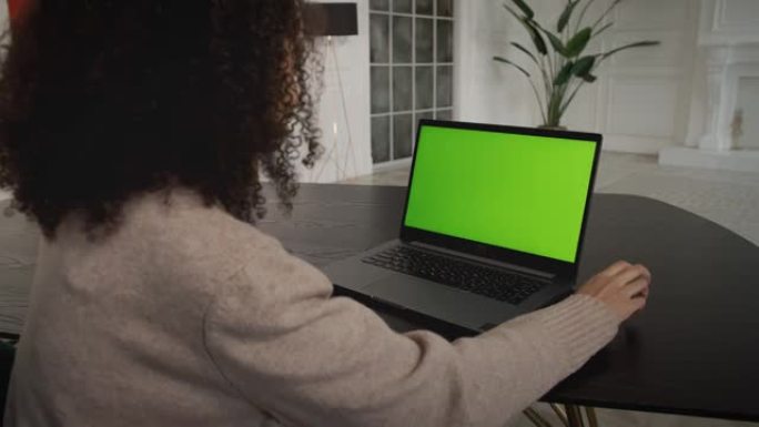 桌子上有笔记本电脑的女人，绿色的样机屏幕