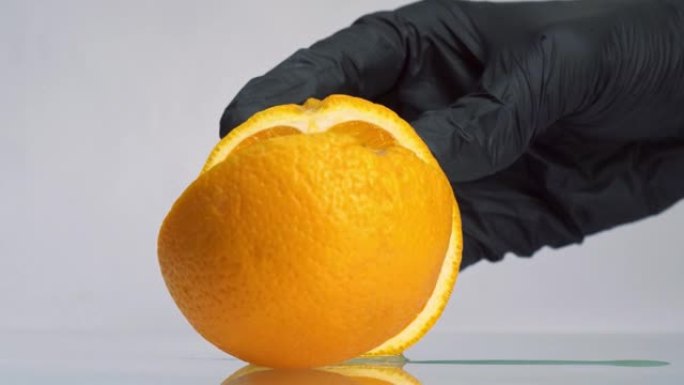 戴着黑手套的男人用大刀将橙色水果切成薄片。橙色切成两部分