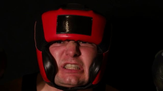 黑色背景上的愤怒男性拳击手。拳击手的肖像。
