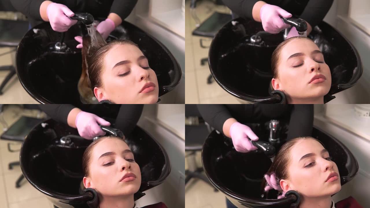 一个戴着粉红色手套的理发师用黑色脸盆洗客户的头发。