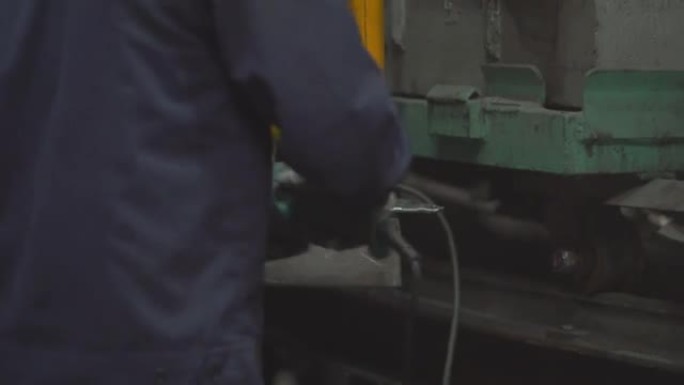 技师用焊接气体进行金属切割，在金属切割过程中研磨落在地板上的金属火花，在工厂内努力拆除高处的金属结构