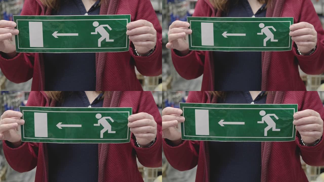 女人举着指示紧急出口的标志。双手特写镜头