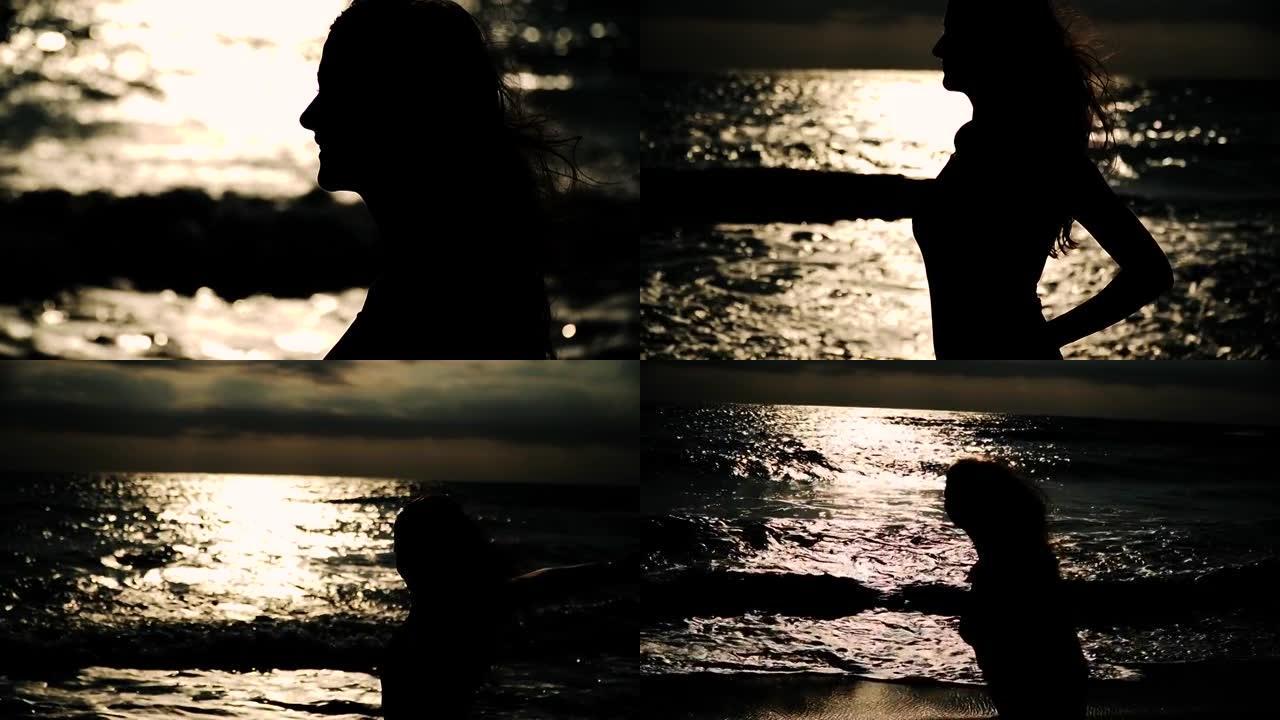 海边一个女人的剪影。用高光和光色对着太阳。头发在风中飞翔