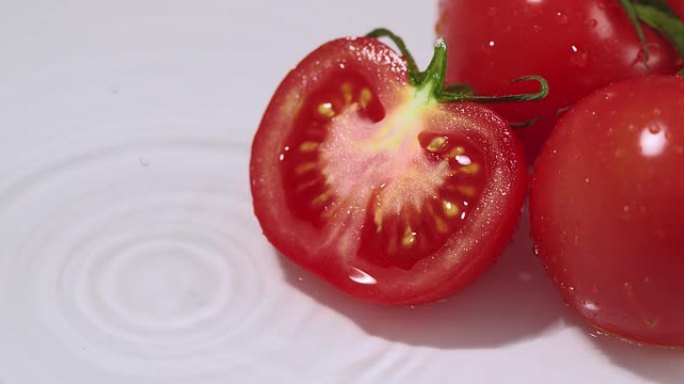 新鲜多汁的意大利西红柿躺在水中，水滴落下。天然闪亮生物有机蔬菜健康饮食