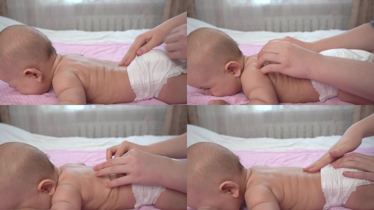 妈妈给躺在床上的新生儿做背部按摩。
