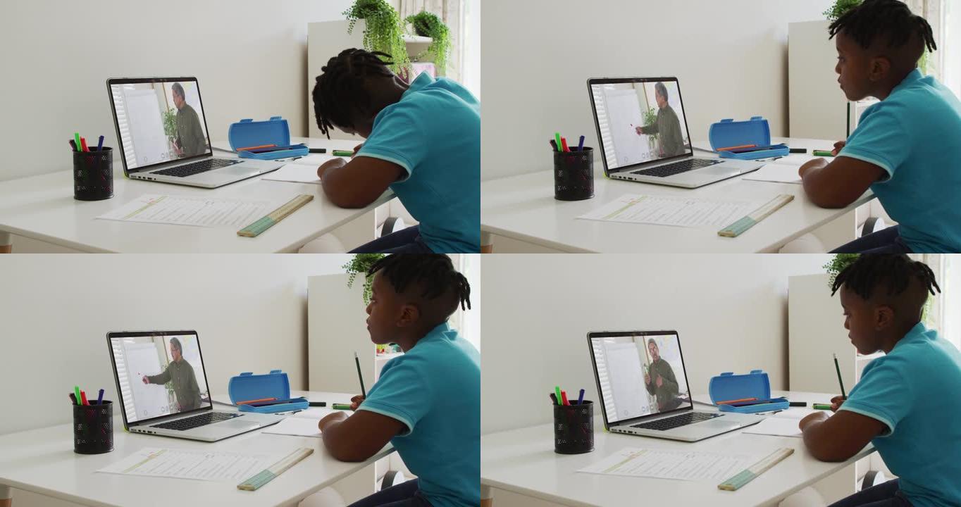 非裔美国男孩在家里用笔记本电脑与男老师进行视频通话时做作业
