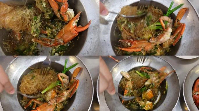 手在锅底将粉丝玻璃面条，蓝蟹鸡蛋和肉与香草菜混合在一起泰国中国菜