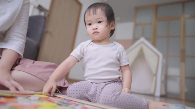 母亲和孩子一起在家里的地板上玩五颜六色的木制磁铁块，抚养一个亚洲人的孩子
