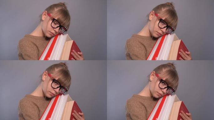 可爱的累了的书呆子学生女孩戴眼镜和一堆书