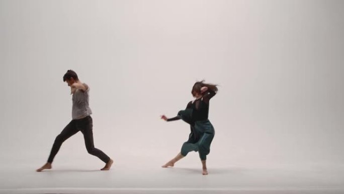 现代编舞的元素，由一对年轻的舞者在白色工作室背景下表演。男人和女人热情地跳舞，用舞蹈表达自己的感受。
