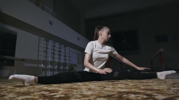乌克兰Ternopil，2019年9月29日: 年轻的柔韧出汗的女体操运动员在体操馆努力锻炼时做劈裂