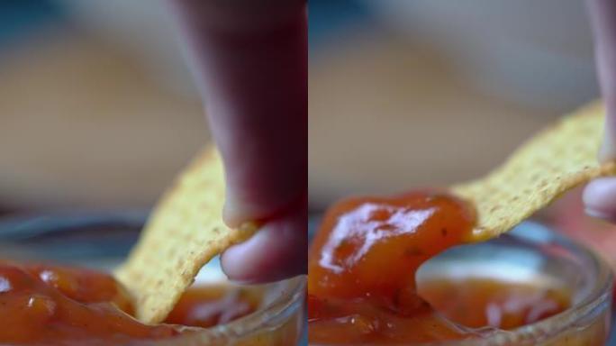 萨尔萨酱蘸玉米饼的特写镜头。垂直射击