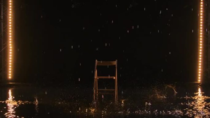 在空旷的黑暗工作室中，一把木椅在雨中站立在水面上。黄光照亮的雨滴落下，鼓在椅子上。慢动作