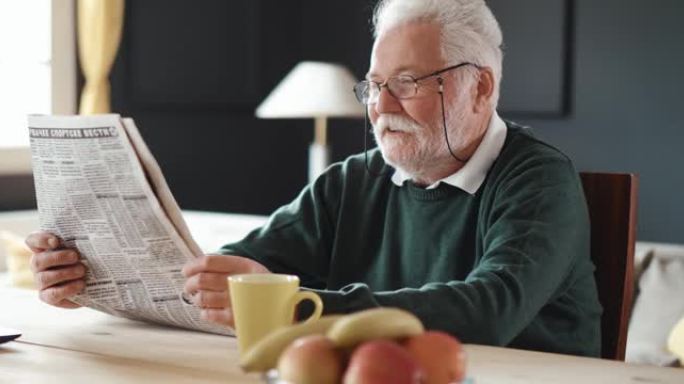 资深微笑的爷爷看报纸，喝咖啡。退休早晨例行公事