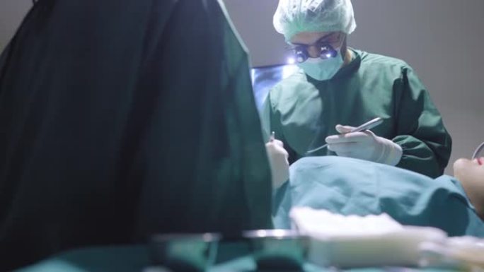 在外科医生和妇女援助的肩膀上，在压力下共同努力挽救她的生命亚洲女性患者躺在医院手术室的床上，以达到生