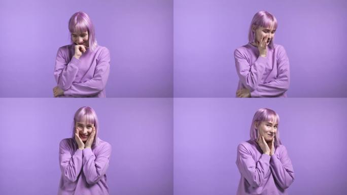 年轻害羞的女人，染成紫色的发型，看着镜头，调情。紫色工作室背景上的美丽模特女孩。