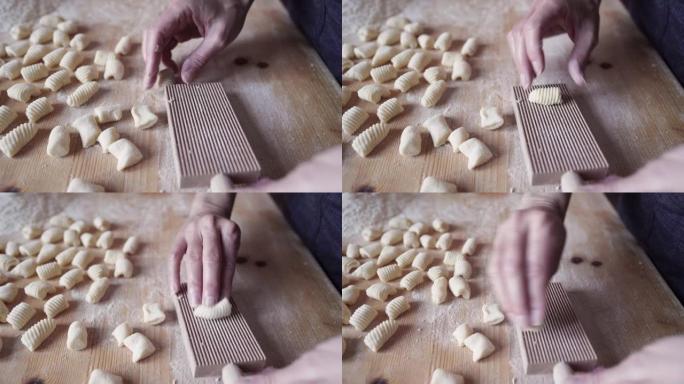 传统意大利面食自制素食汤团土豆制作过程的特写镜头。女人在木制规则板工具上煮面团。在家里玩得开心，用你