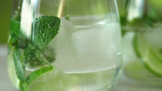 玻璃莫吉托鸡尾酒。将苏打水与新鲜的石灰，薄荷和冰一起用勺子搅拌。碳酸饮料。
