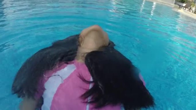 快乐的亚洲女孩漂浮在游泳池里的水上，夏天的生活方式理念。