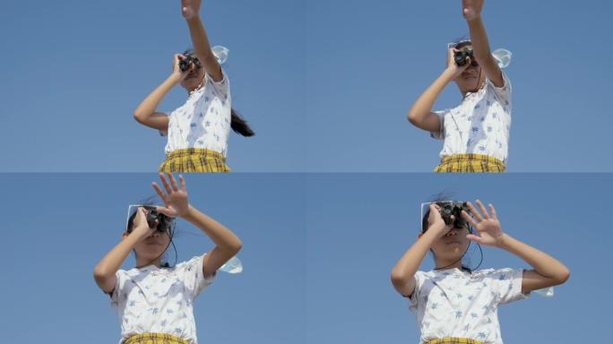 亚洲女孩用双筒望远镜看着山顶上的蓝天，生活方式的概念。