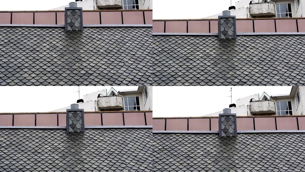 欧洲房屋屋顶和烟囱上方的灰色瓷砖鱼鳞瓷砖屋顶