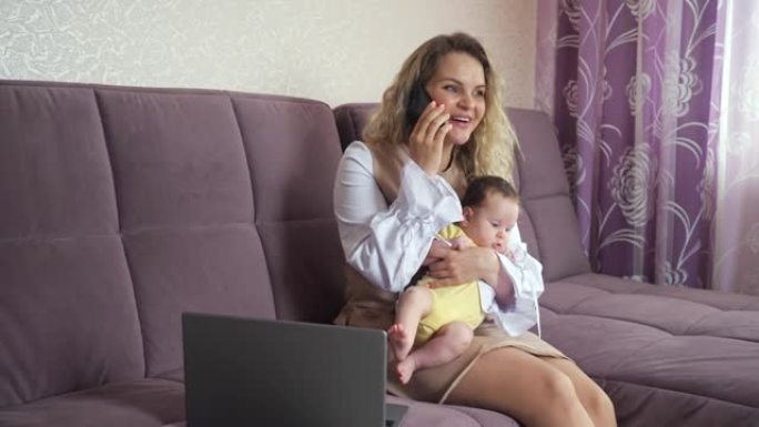 快乐的母亲在智能手机上谈论将女婴抱在怀里