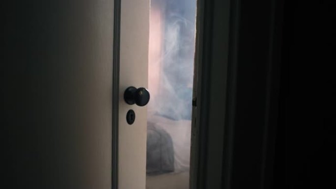 在房屋火灾期间，透过门缝凝视着浓烟弥漫的卧室