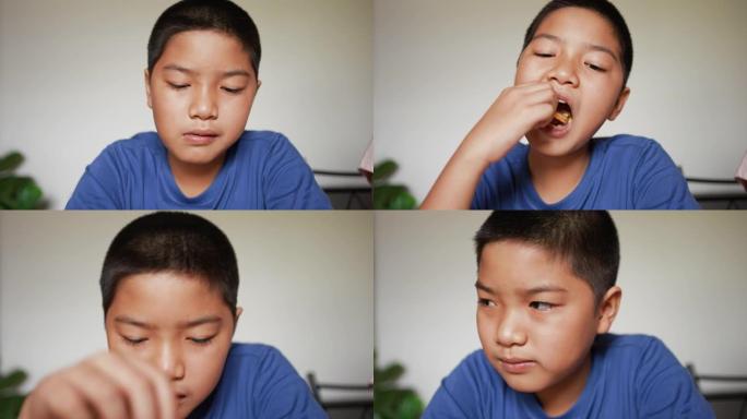 年轻的亚洲男孩在午餐后吃面包饼干的慢动作场景，对生活方式的孩子概念感到欣喜若狂