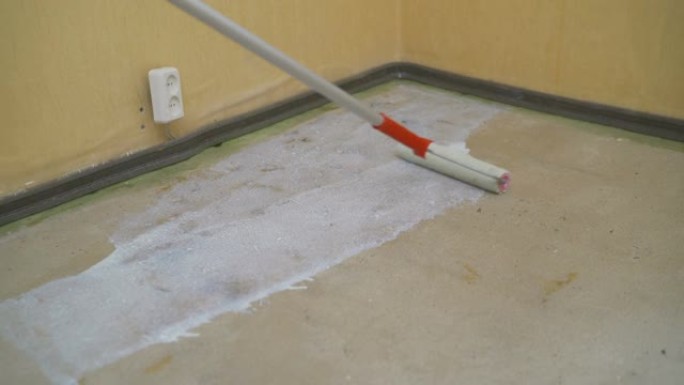 工人将滚筒底漆放在未完工公寓房间的混凝土地板上。公寓里的修理，用滚筒铺底