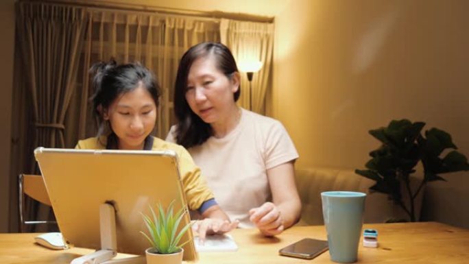 快乐的亚洲女孩帮助母亲填写信用卡号以结清账单或在家在线购物，生活方式概念。