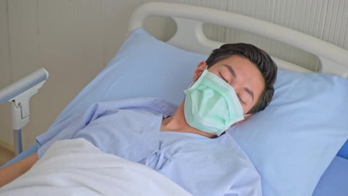 身体不适的年轻亚洲男性患者咳嗽，躺在医院的病床上休息后因感冒和流感而康复。在covid 19期间佩戴