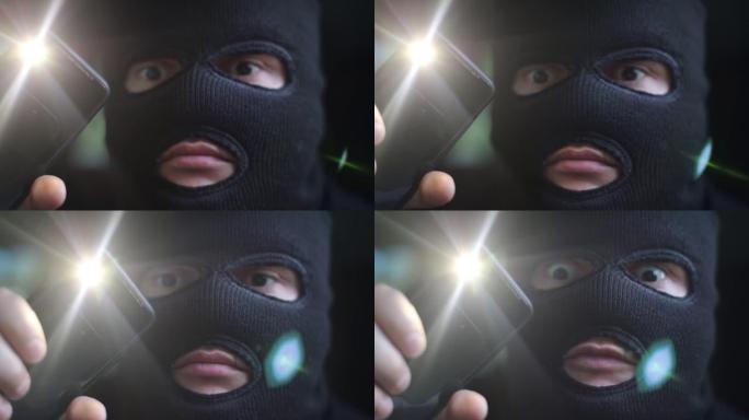 恐怖分子戴着黑色面具，手里拿着手电筒