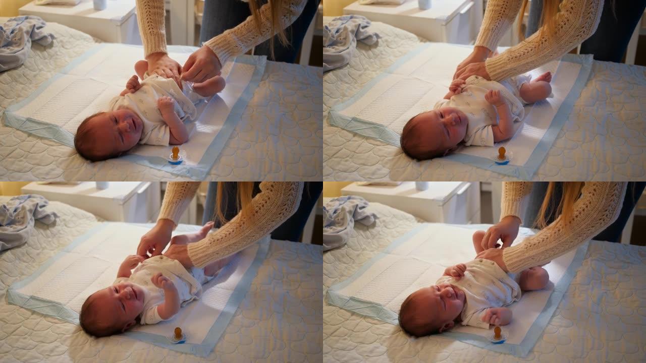 年轻的母亲给晚上在床上哭泣的新生男婴换了凌乱的尿布。婴儿卫生，充满爱心和关怀的父母和家庭幸福的概念。