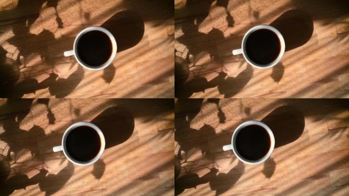 多莉拍摄了一个黑色咖啡杯，上面有天然蒸汽和气泡，在阳光明媚的早晨场景中从正上方拍摄