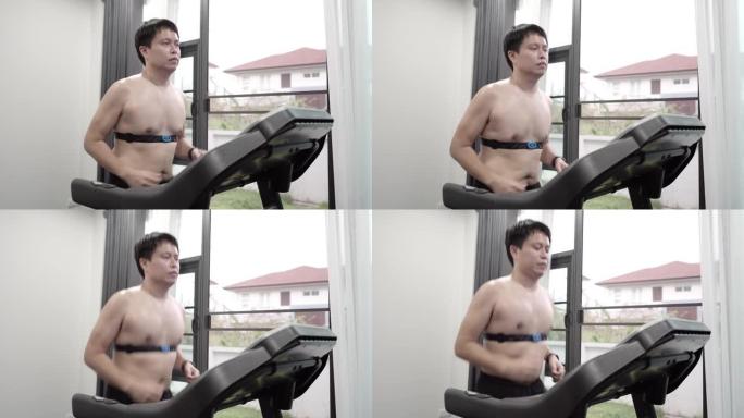 亚洲男子在家里跑步机上跑步时戴着心率带。