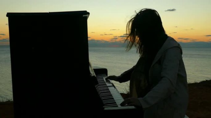 日落时弹钢琴的女孩的剪影
