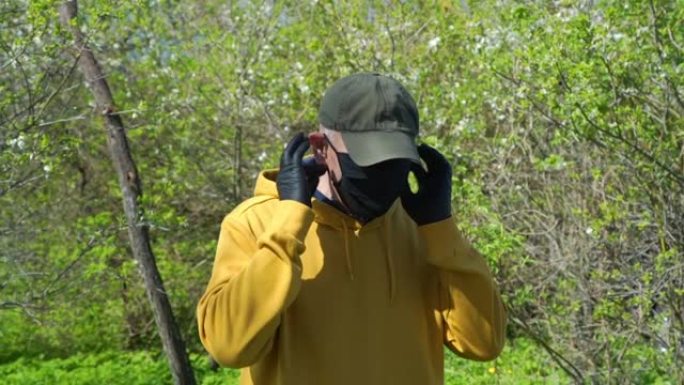 养老金领取者在绿树丛中戴上黑色一次性口罩