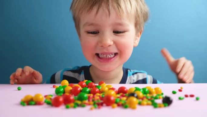 快乐开朗的孩子男孩找到五彩缤纷的糖果。可爱的小男孩很高兴抓到五颜六色的巧克力糖果糖衣。不健康的食物。