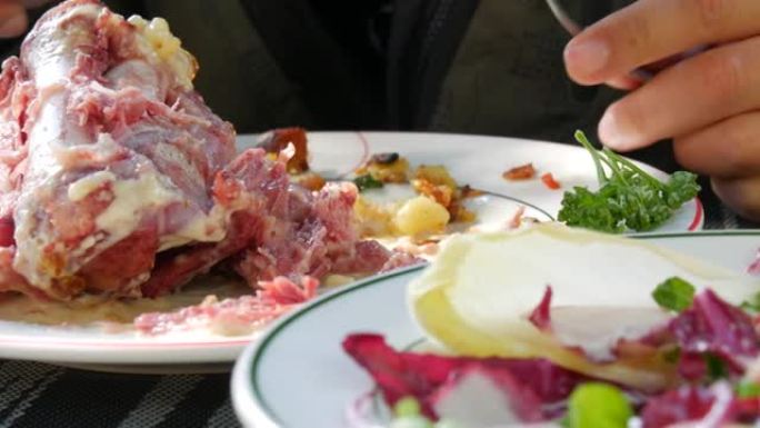 男性用刀叉切割手，在餐厅吃新鲜烹制的美味猪脚