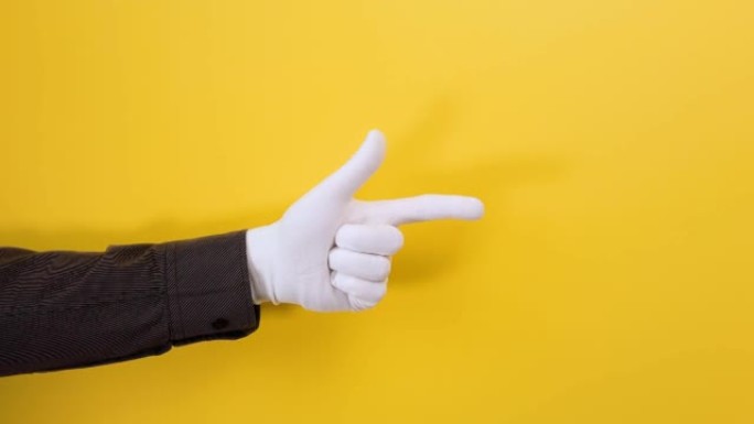 雄性的白手套手指向正确的方向。特写。黄色背景