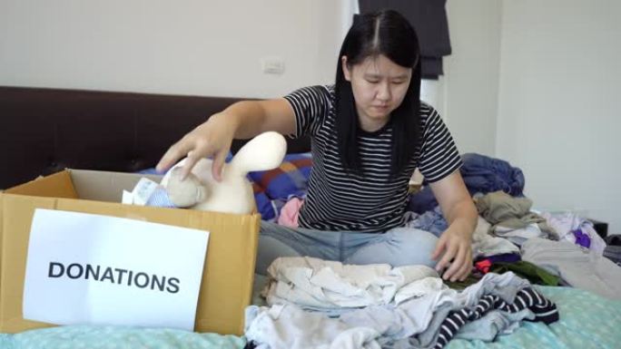 亚洲妇女整理衣服放在捐款箱里。