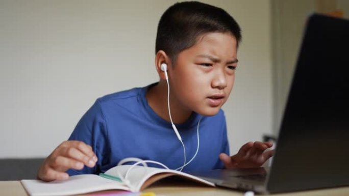 亚洲年轻男孩的慢动作场景练习口语技能，同时加入学校的电子学习网站，在家庭教育和技术概念检疫期间进行听