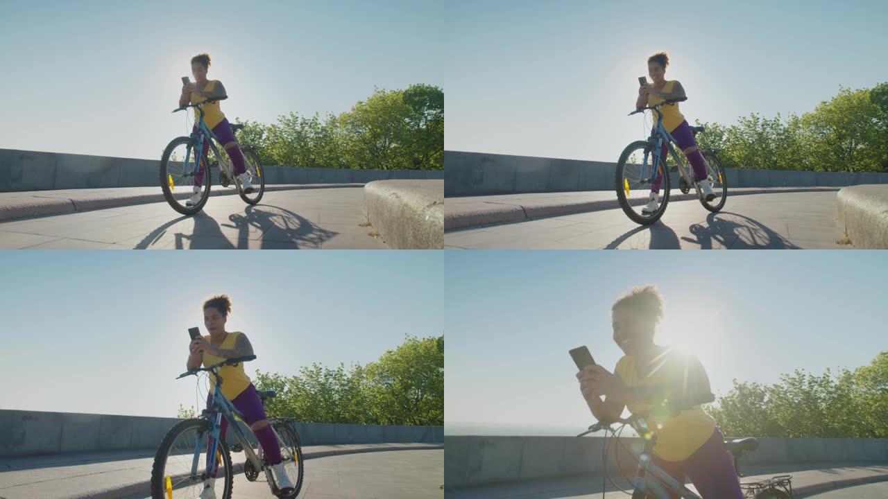 黎明时，漂亮的女自行车手靠在自行车车把上的手机短信上