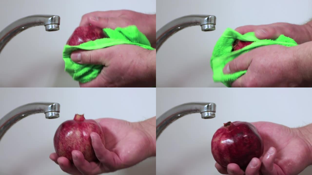 特写男性双手用绿色毛巾擦干水果。