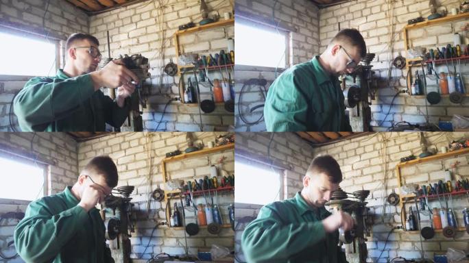 工作服的年轻修理工在车库检查车辆细节。疲惫的工人机械师脱下防护眼镜，擦去额头上的汗水。在车间工作的男