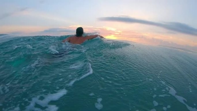 日出冲浪板。年轻人手持飞机在日出时划入海洋