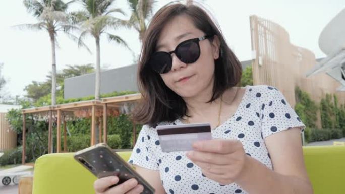 快乐的亚洲女人通过智能手机上的信用卡付款，在线购物生活方式概念。