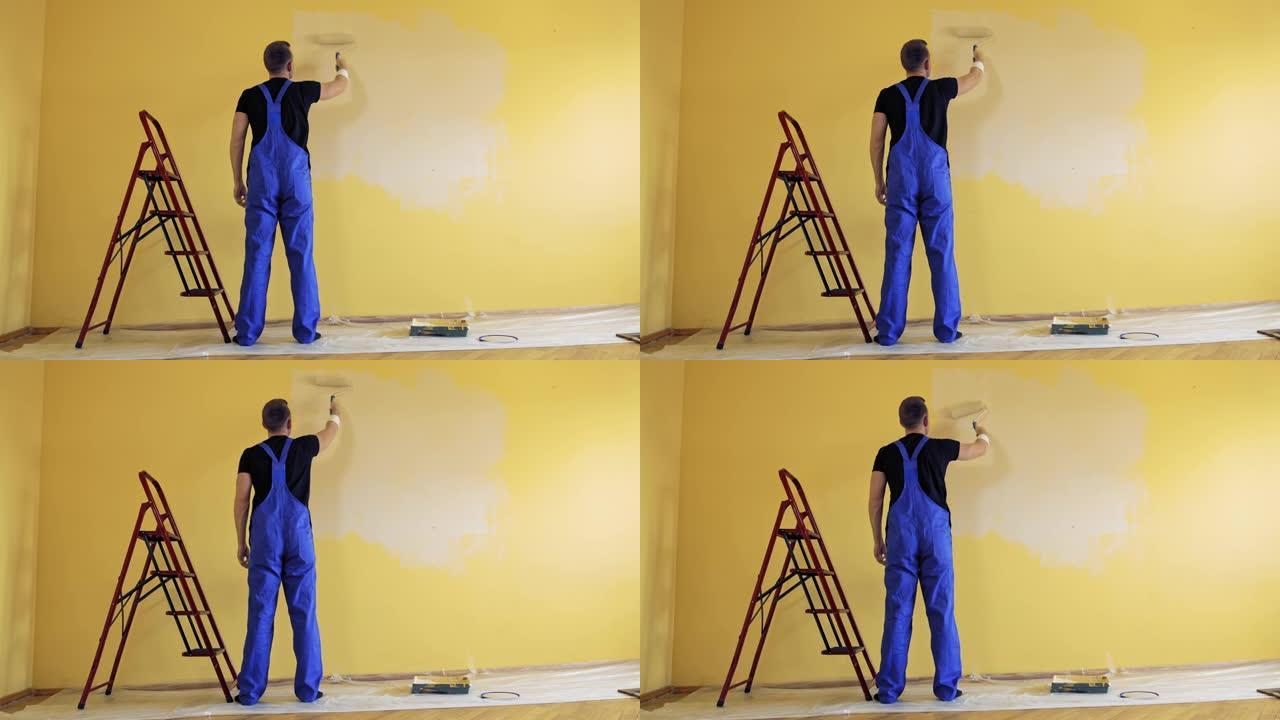 画家在黄墙上画画。维修、建筑和家居概念。